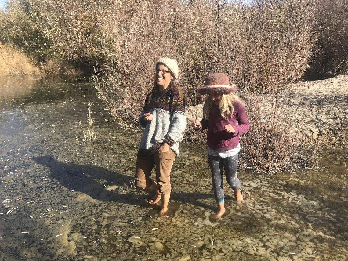 Audrey Taub and her daughter, Hazel Taub-Finlayson, wade through water pooled along the Salinas River in Atascadero.