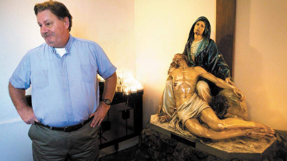 The Rev. Russ Brown of Mission San Luis Obispo stands next to a statue that was vandalized Tuesday.