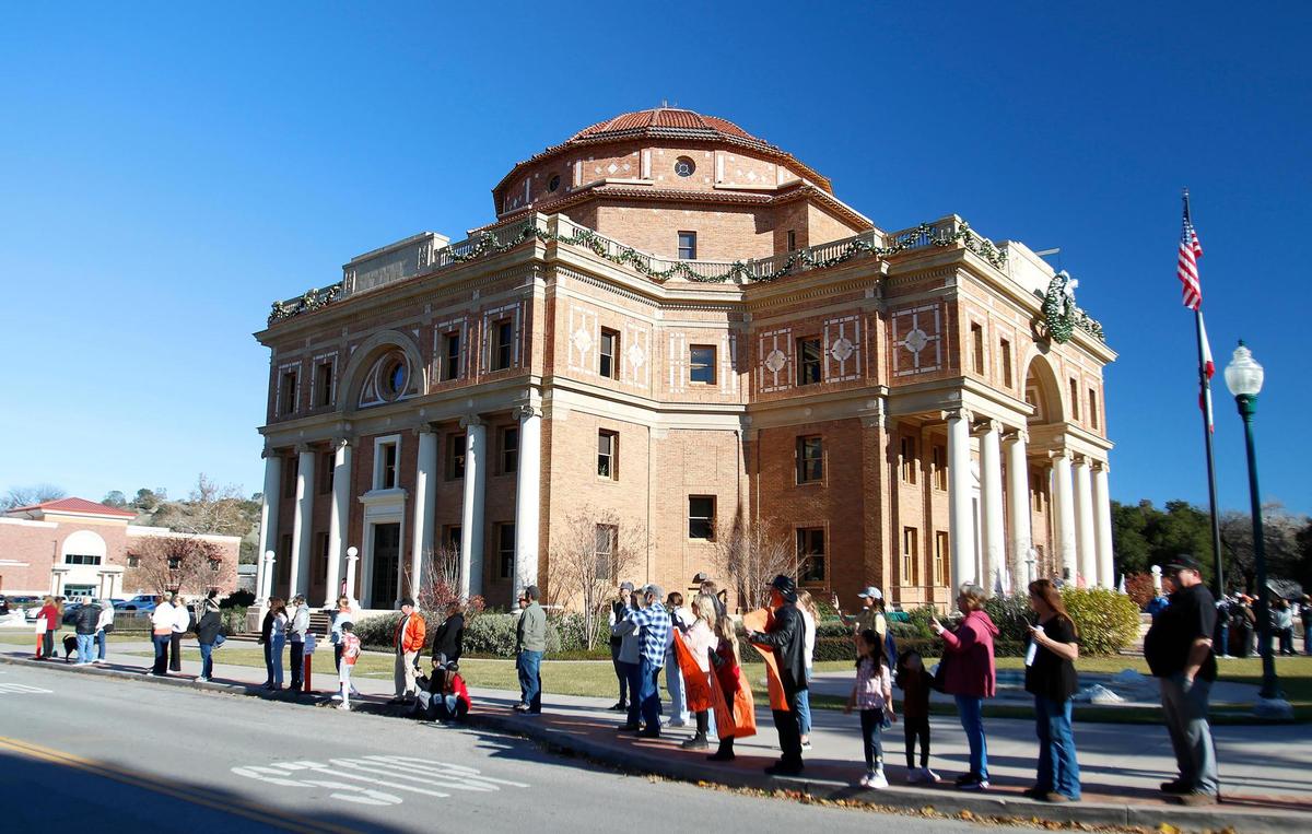 Community members line the streets around City Hall during a parade to celebrate Atascadero High School’s state champion athletes, including the football team and cross country runner Frannie Perry, on Wednesday, Dec. 21, 2022.