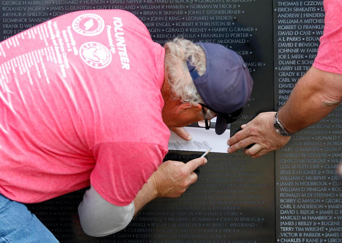 Charles Belmont, a volunteer at The Wall That Heals, helps a Morro Bay woman make an etching of a name at the traveling Vietnam War memorial in San Luis Obispo on Saturday, March 18, 2023.
