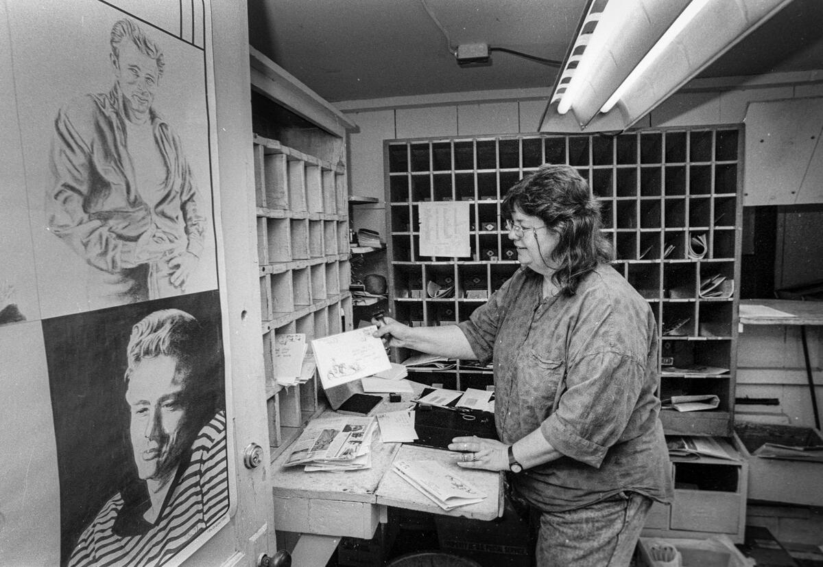 Bonnie Speer, postal assistant at the Cholame Post office March 1, 1991 sorts mail with James Dean posters on the wall. The office was closed in 1994 and at the time served 20 families with post office boxes and another 20 via delivery.