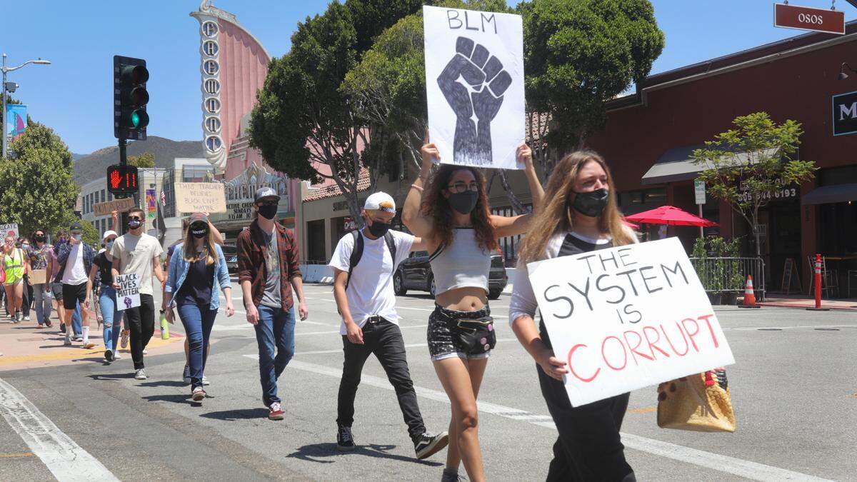 A group of marchers move down Monterey Street with the traffic light during a silent protest on July 25.