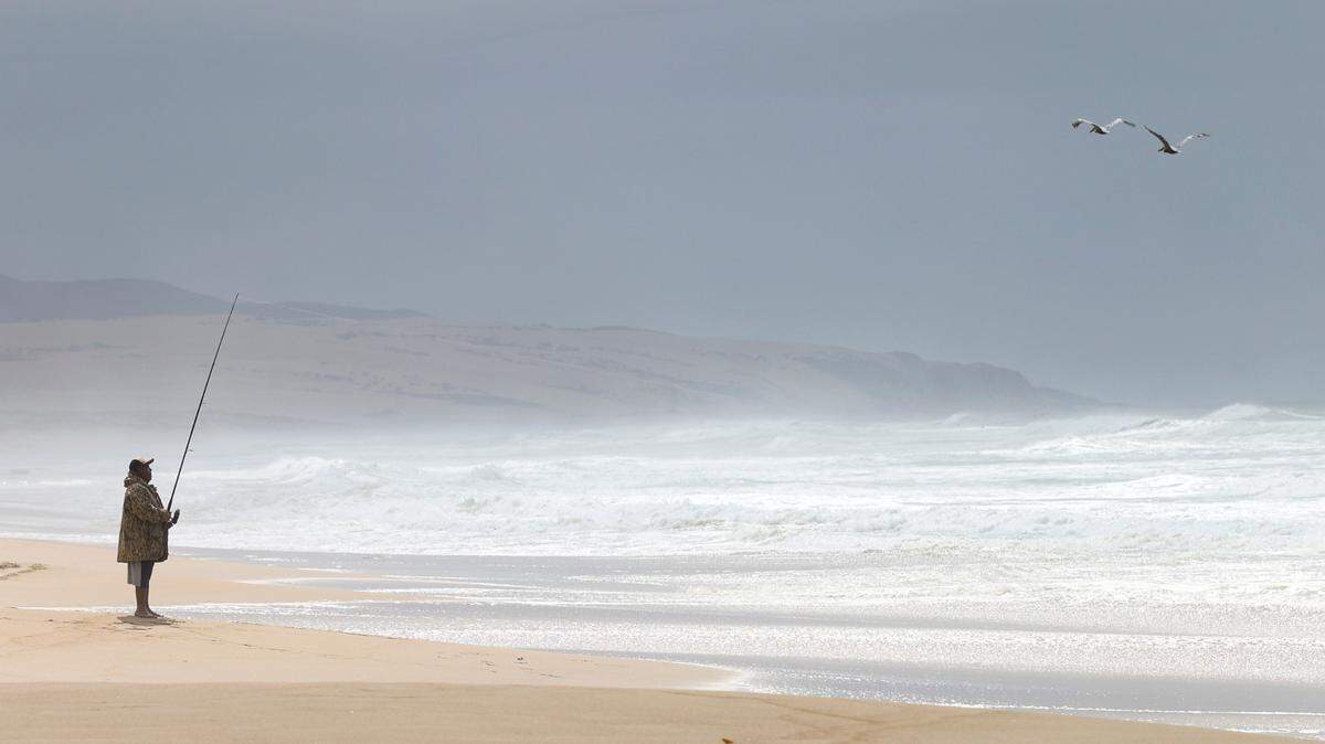 Manuel Montano fishes for striper at the Guadalupe-Nipomo Dunes as clouds roll across the coast.