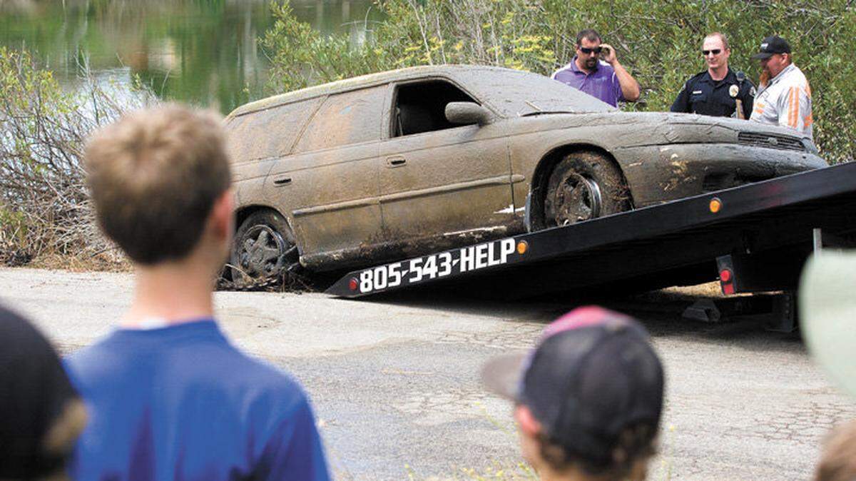 Spectators gather to watch the removal of a car found submerged in San Luis Obispo's Laguna Lake on Monday, July 28.