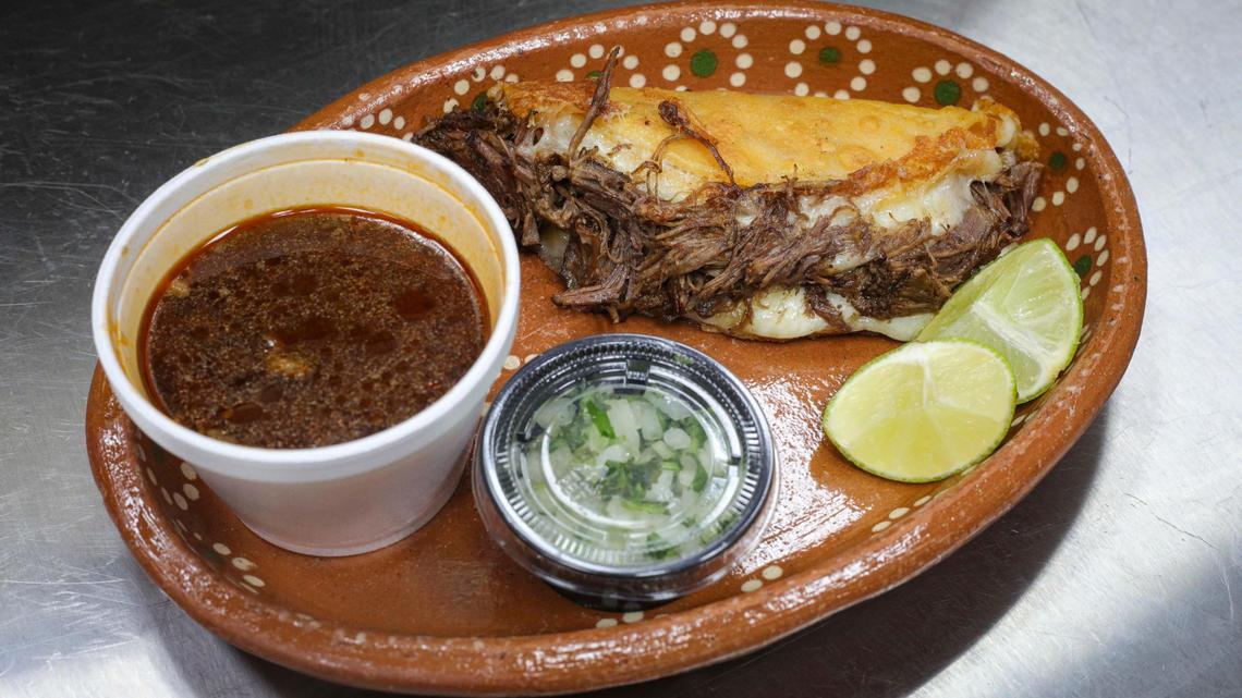 La quesabirria incluye una tortilla de maíz, birria, queso, una guarnición de caldo, cilantro cebolla y limones. Azteca Market en Atascadero es un restaurante y mercado de fusión mexicano-guatemalteca, visto aquí el 29 de noviembre de 2023.