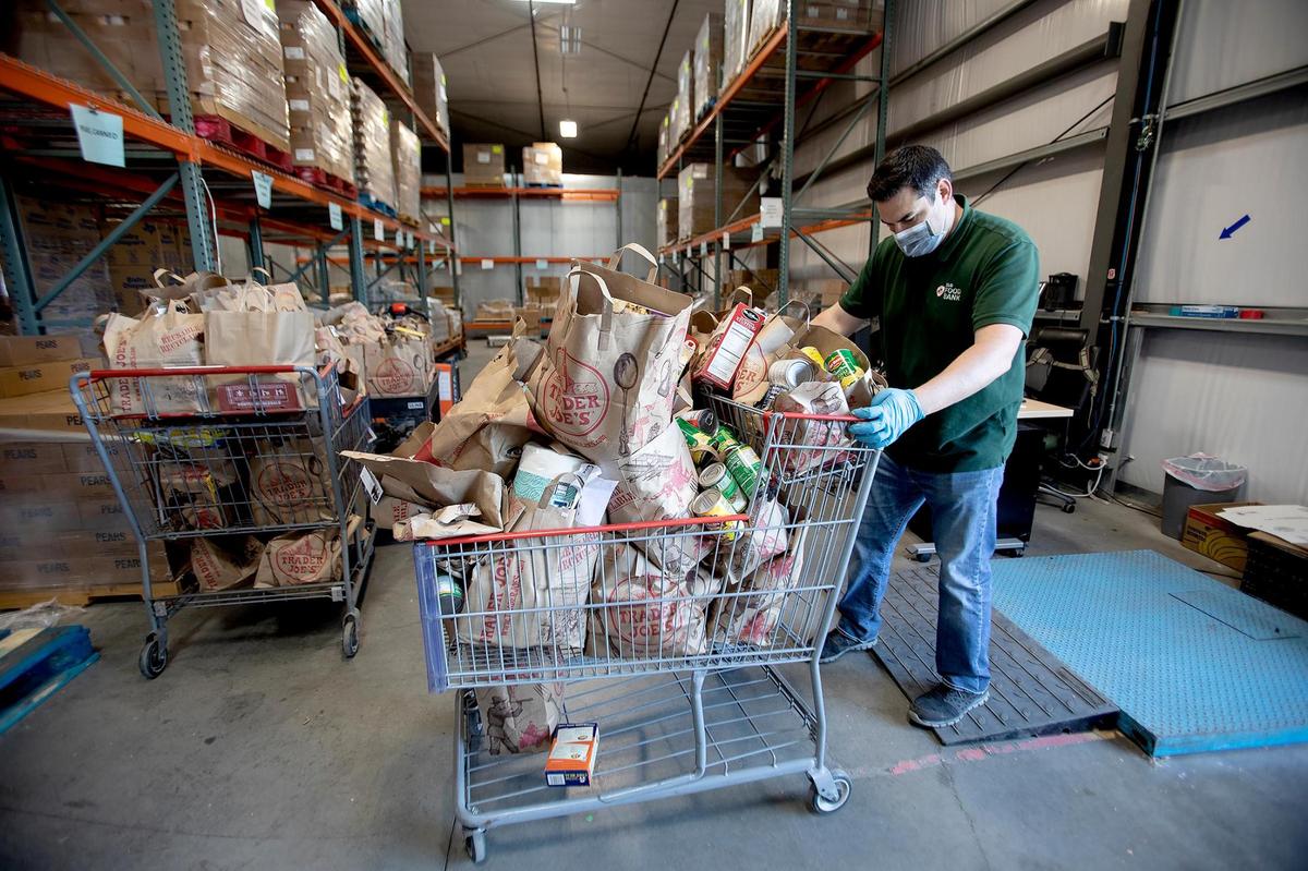 Thomas Loots, a clerk with the SLO Food Bank, weighs a grocery cart holding folding donated by the Christa Lowery Real Estate of Pismo Beach. The SLO Food Bank has dealt with waves of demand for assistance due to the coronavirus pandemic, inflation and changes to state benefits.