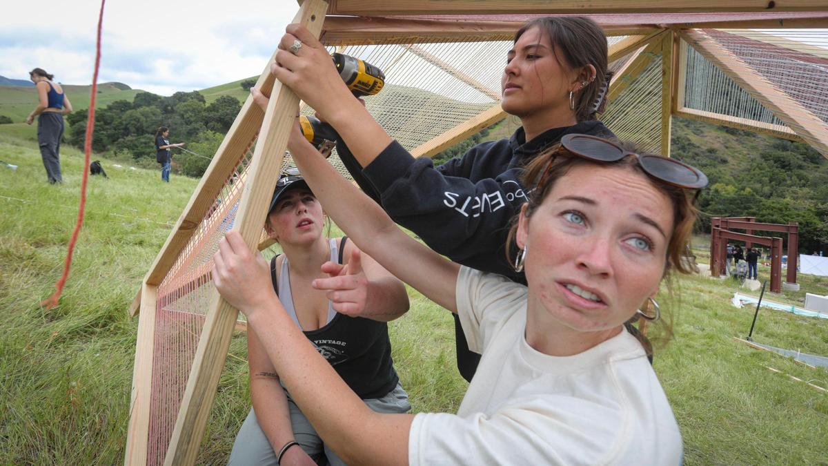 Cuesta College students assemble a hinged wood and yarn structure titled SLOLINK, from left: Eliana Cunningham, Ali Karner and Taylor Jones assemble. Architecture students from throughout the west came to Poly Canyon participate in Design Village on the Cal Poly campus on April 25, 2025.