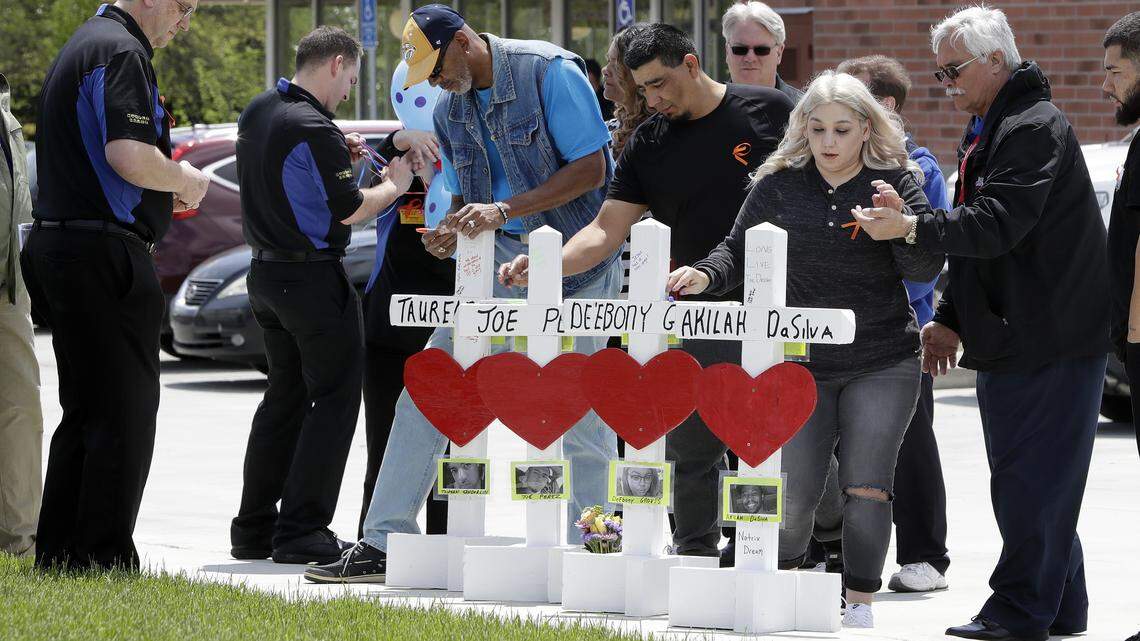 Family members of the four victims killed at a Waffle House restaurant shooting write messages on wooden crosses set up outside the business on April 25, 2018, in Nashville, Tennessee.