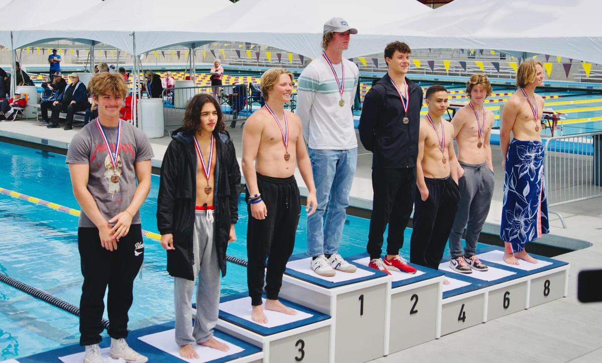 Justin Dozeal stands in the middle on the first-place podium after winning a meet for San Luis Obispo High School.