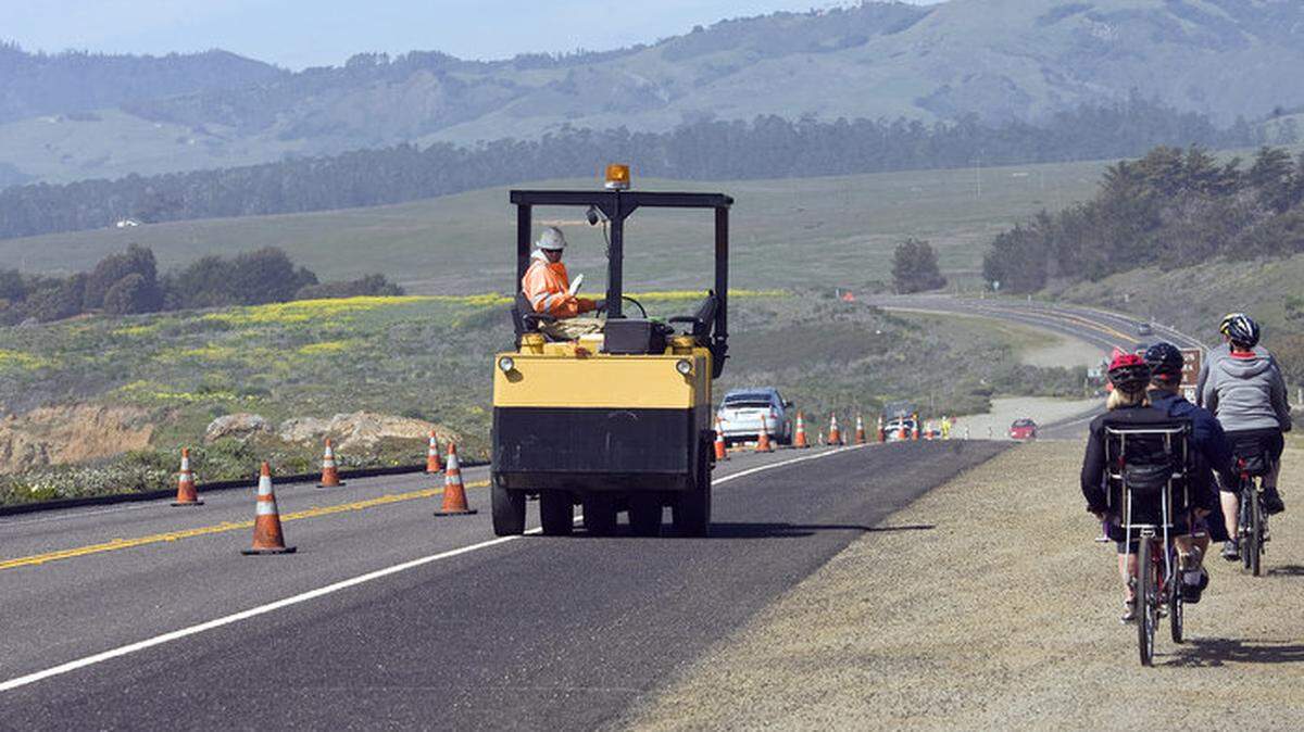 A Caltrans worker waves to cyclists as he rolls over the bike lane north of Cambria on Highway 1 on Tuesday.