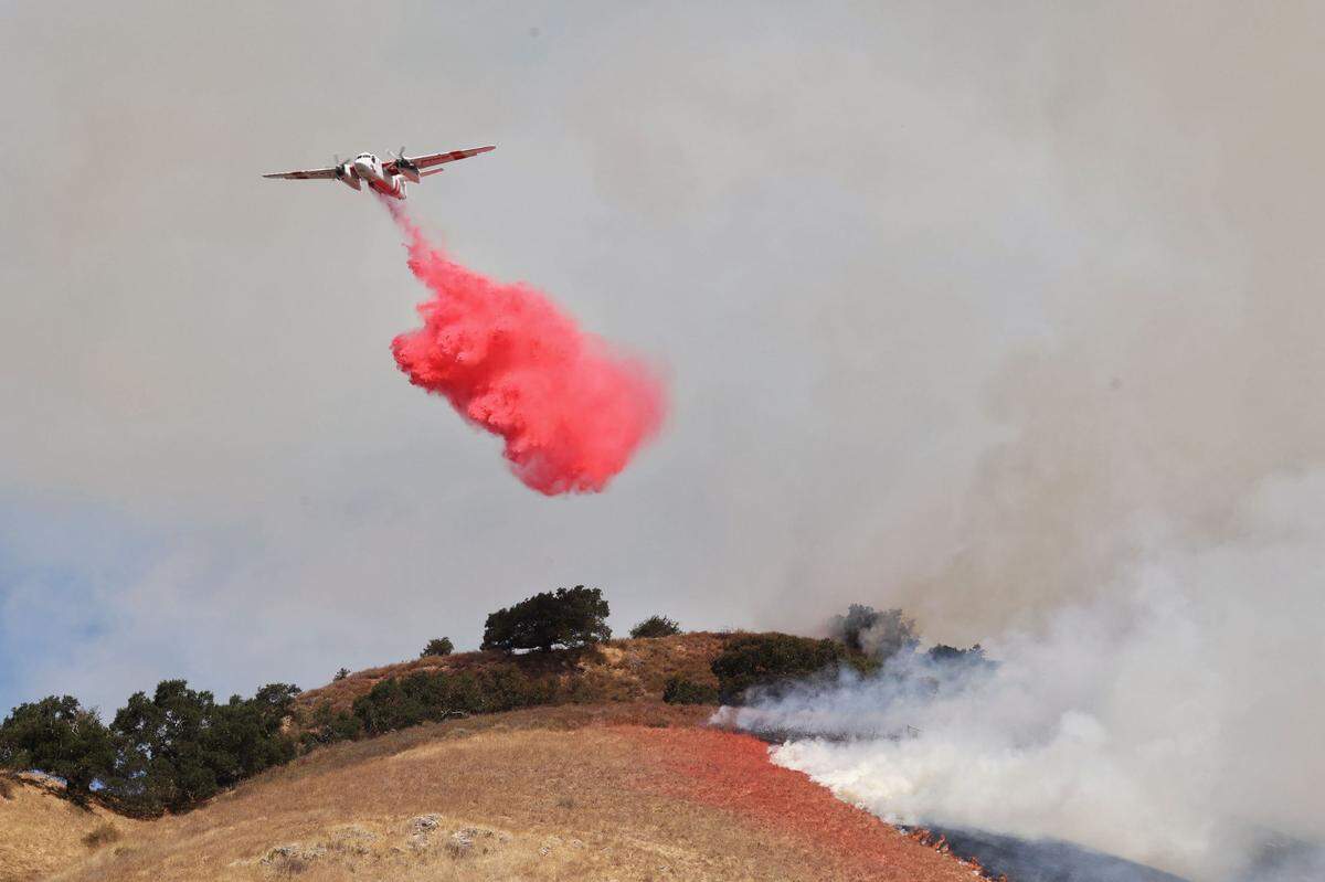 A Cal Fire plane drops retardant on a vegetation fire burning on a hill along southbound Highway 101 near Hawk Hill Lane at the base of the Cuesta Grade in San Luis Obispo on Sept. 3, 2024.