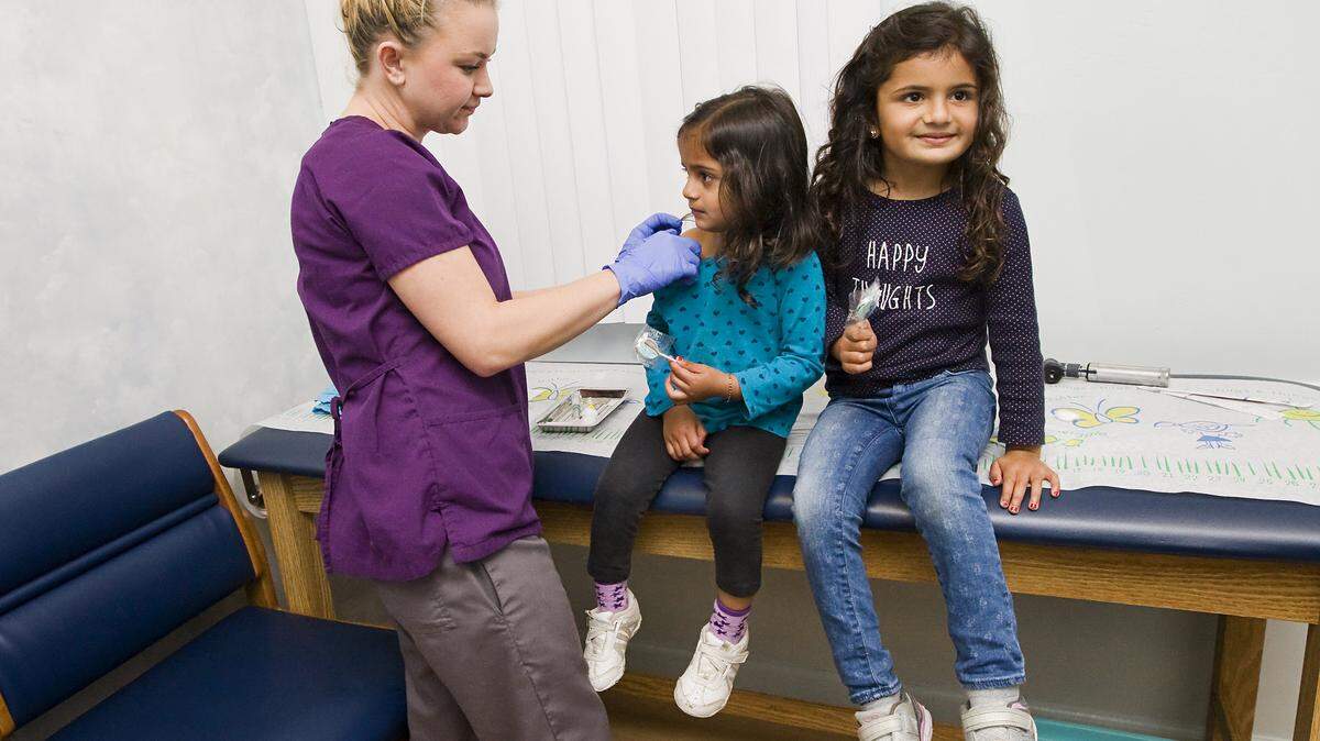 Medical assistant Kim Copeland gives flu shots and suckers to Anaya Patel, 2, left, and her sister, Ariya, 4, at Dr. Rene Bravo's office in San Luis Obispo on Thursday.
