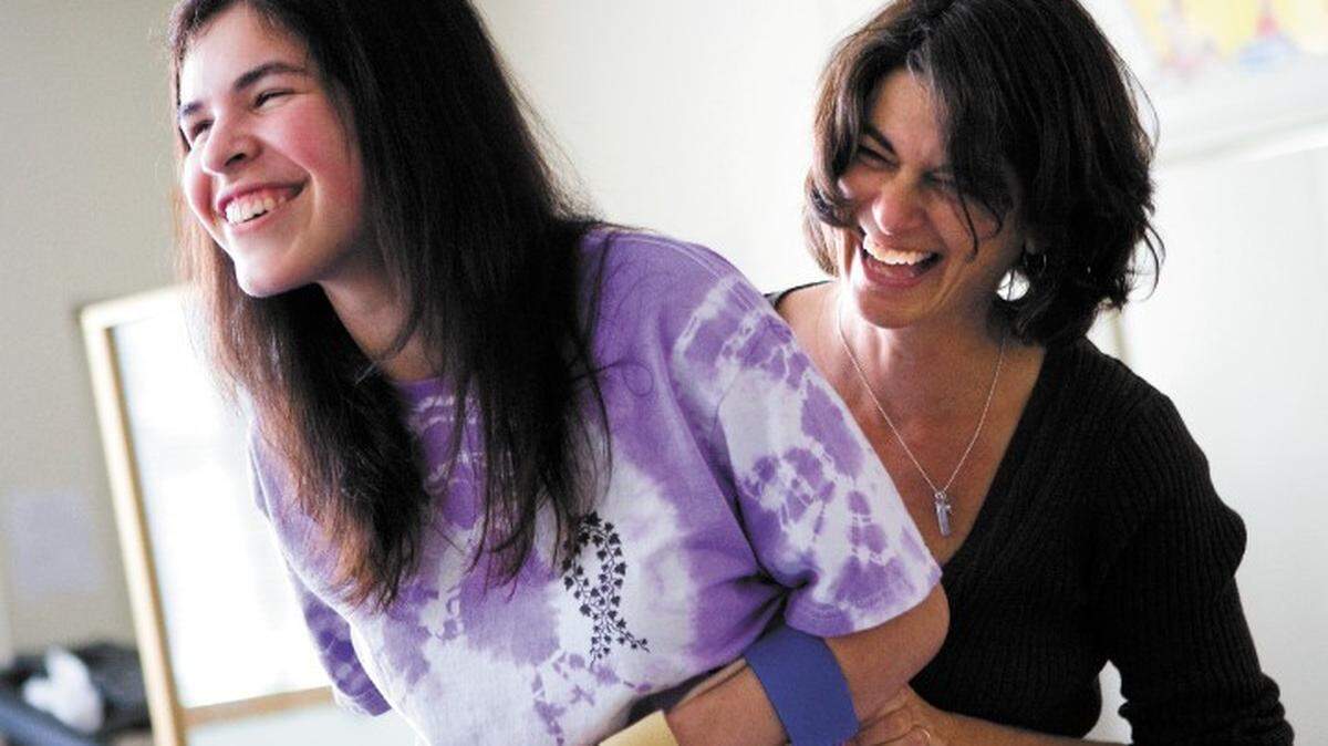 Ivy Alvarado enjoys a light moment during a physical therapy session recently with Linda Wolff.