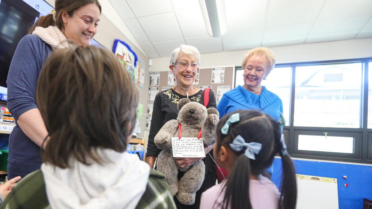 From the left, librarian Lauren Conklin, San Simeon native Marj Sewell and Cambria resident Pat Moreno chat with students at Cambria Grammar School on Dec. 13, 2022. Sewell, 90, is donating Teddie, a teddy bear she made in the 1970s and used in her classrooms as a teacher for three decades,
