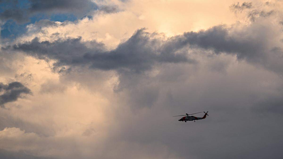 A U.S. Coast Guard Sikorsky MH-60T Jayhawk helicopter flies out to sea toward a storm.
