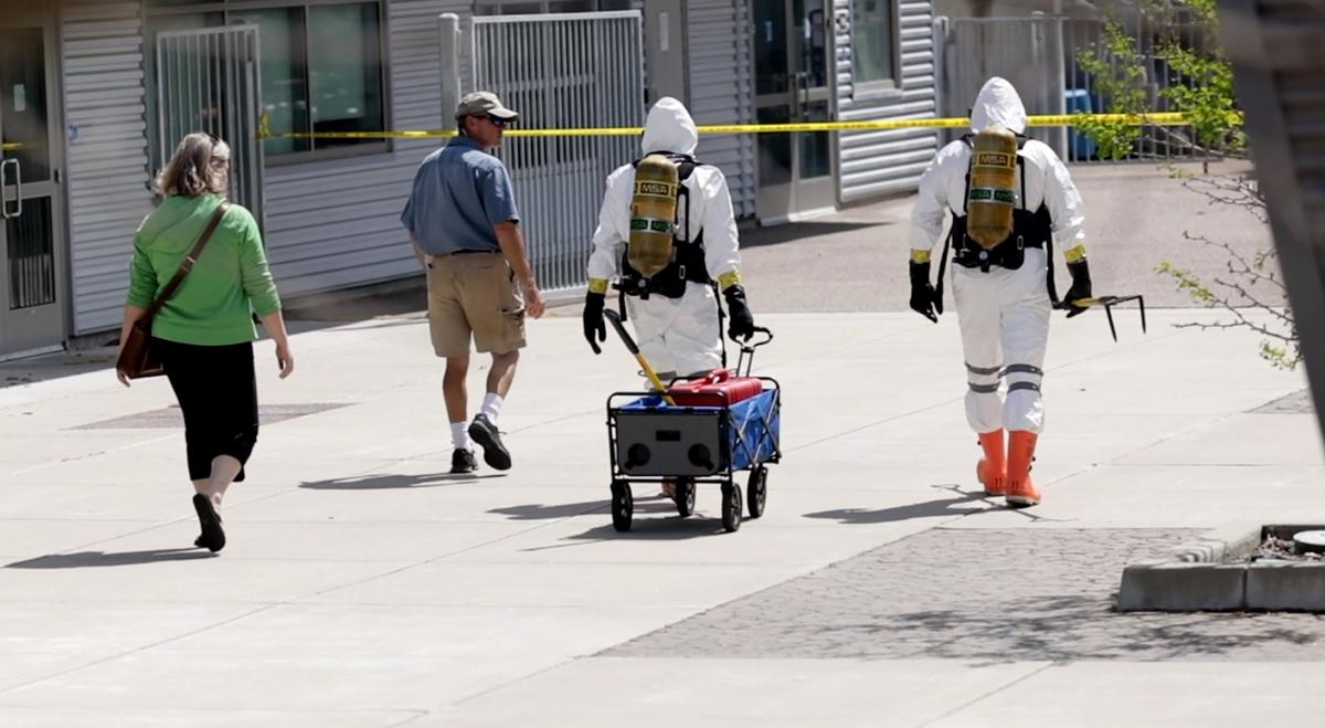 Members of a hazardous material team walk between the engineering buildings at Cal Poly to investigate a suspicious yellowish liquid bubbling up in a parking lot on Monday. It turned out to be water.