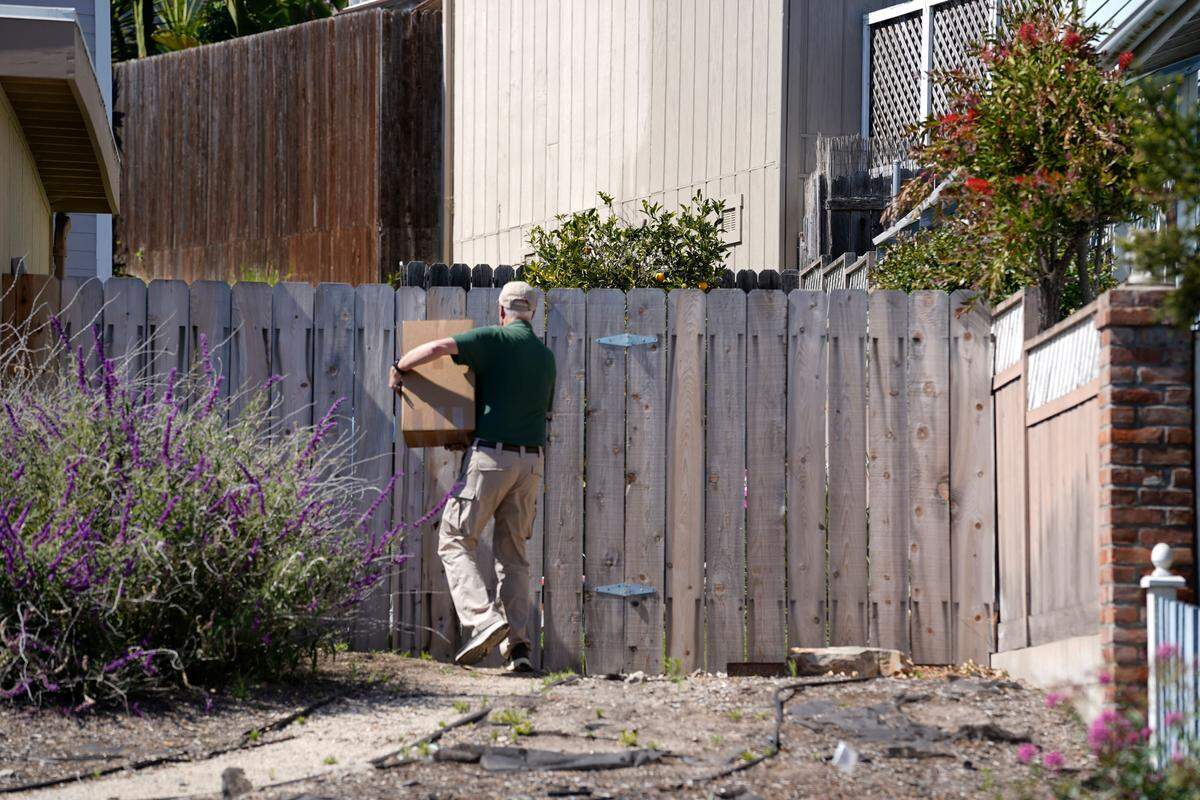Boxes are carried into the backyard of the property next door to Susan Flores’ home on East Branch Street in Arroyo Grande as part of the Kristin Smart investigation on May 6, 2026. Susan Flores is the mother of Paul Flores, who was convicted of Smart’s murder in 2022.