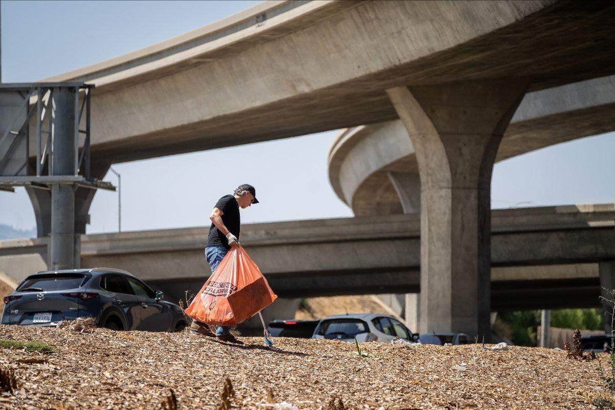 California Gov. Gavin Newsom helps clear away remnants of a homeless encampment in Los Angeles on Aug. 8, 2024. The camp was dismantled by Caltrans in response to Newsom’s executive order.