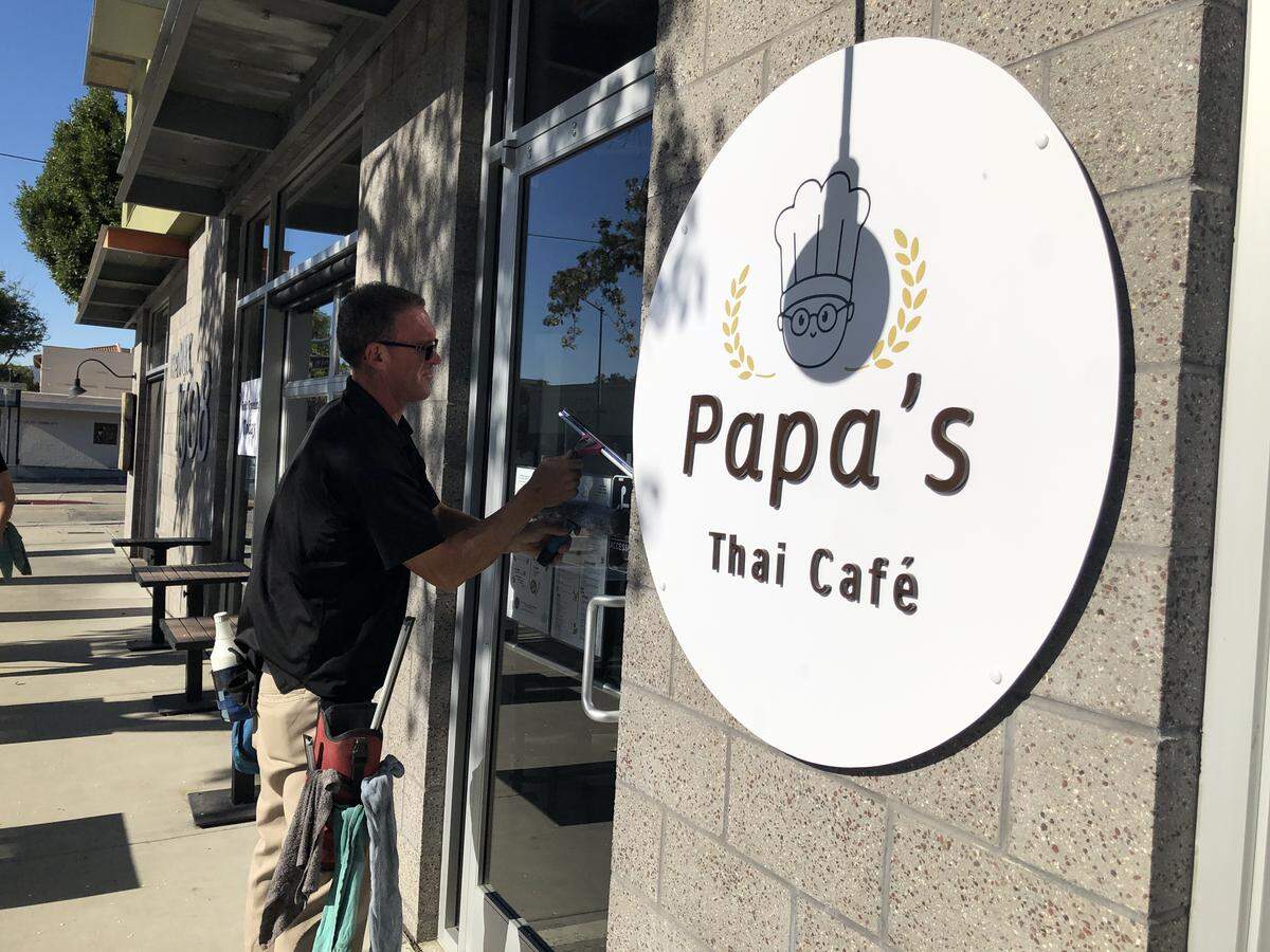 Corey Byler, owner of Crystal Clean A-1 Window Services, cleans a door window of the new Papa’s Thai Cafe in SLO.