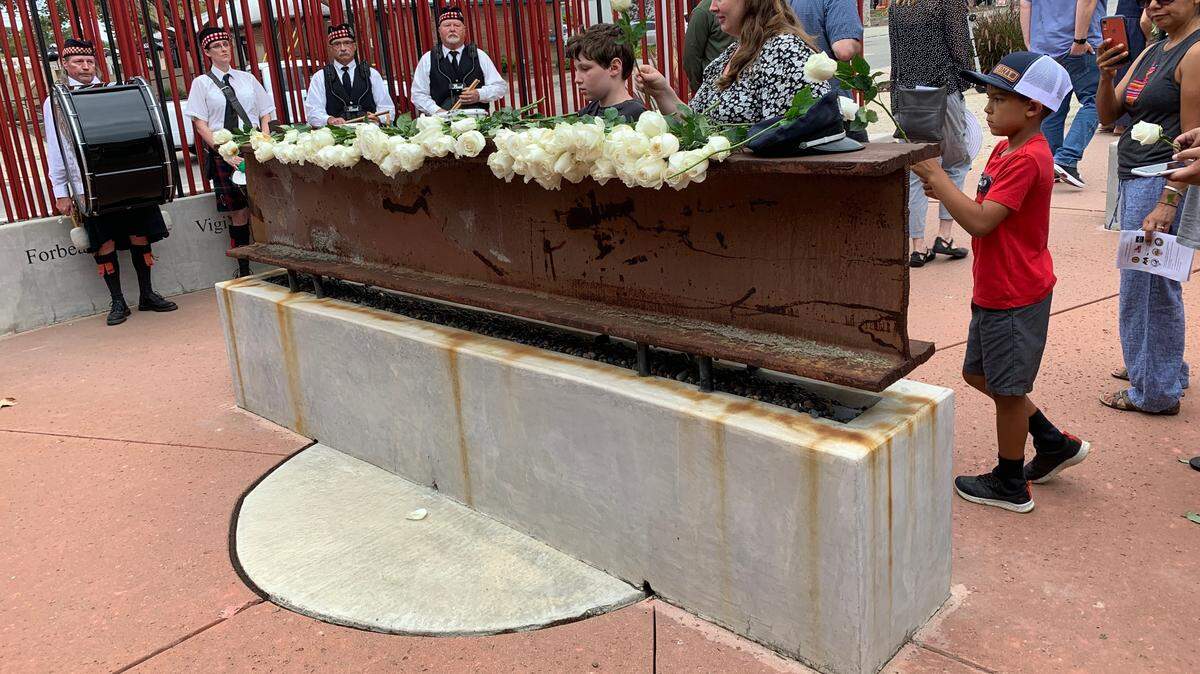 Community members lay white roses on the steel beam at the center of the World Trade Center Memorial in front of Fire Station No. 1 in San Luis Obispo on Sunday, Sept. 11, 2022, as members of Central Coast Pipes and Drums look on. The city held a 9/11 Day of Remembrance ceremony at the site.