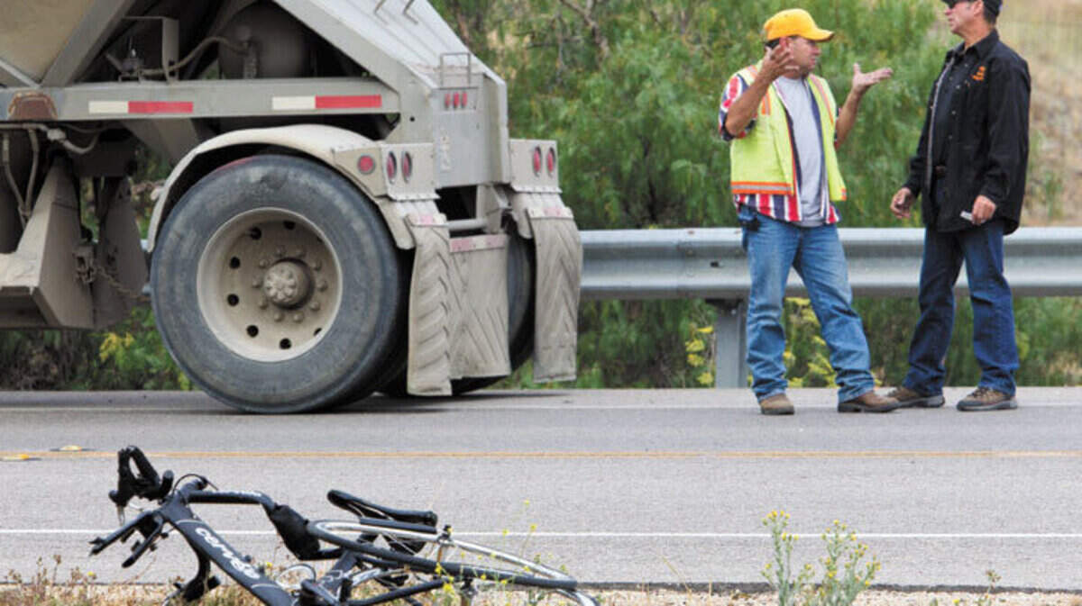 The driver of the truck, left, talks with the trailer owner about the crash that killed a bicyclist  at South Higuera Street and Ontario Road on Wednesday.
