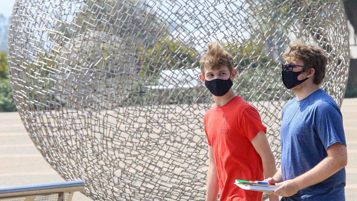 Freshmen Cal Poly students Justin Green, left, and Nicholas Proffitt, right, wear masks and walk by a sculpture outside the Performing Arts Center on Sept, 14.