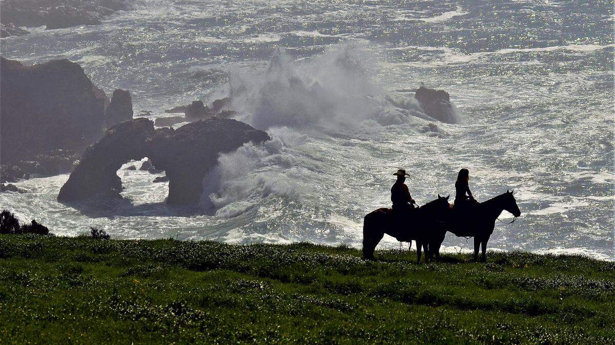 A cowboy and cowgirl riding in tall, green grass along the Pecho Coast, near Diablo Canyon Power Plant.