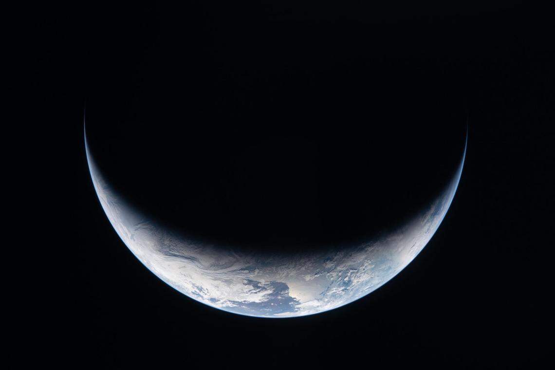A sliver of Earth is illuminated against the blackness of space in this photo taken by an Artemis II crew member through an Orion spacecraft window on the third day of the mission.