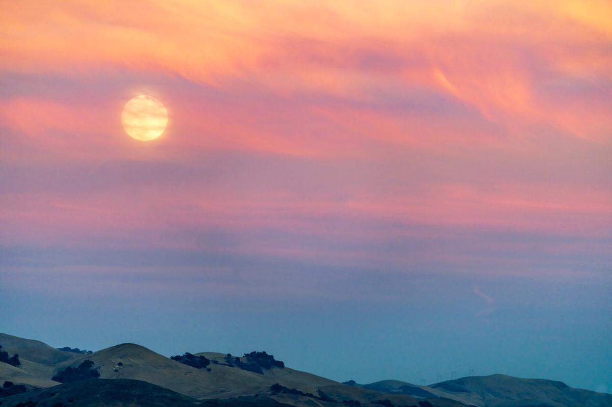 A full moon rises behind strands of clouds this week in a view from Terrace Hill in San Luis Obispo.