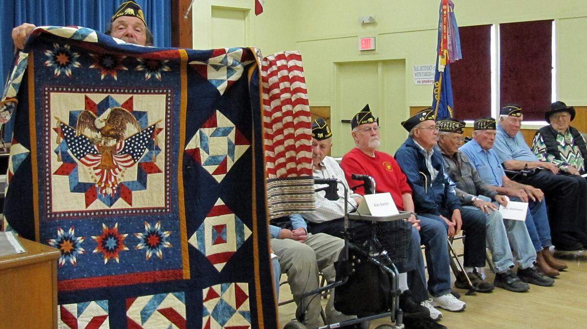 Jay Burbank peers over the award-winning quilt given to him Aug. 7 in a Quilts of Valor ceremony in Cambria. The quilt, one of 10 awarded to veterans that night, was made by Burbank’s friend Leeri Deedon of Morro Bay. The fabric artwork won a sponsored award at a recent Seven Sisters Quilt Show in San Luis Obispo, selected as best representing the colors of America. The red and white fabric to the right of the quilt is a custom-made slipcase for it. Other vets honored with a quilt gift by the Gold Coast Quilt Guild’s Quilt of Valor Project and American Legion Post No. 432 were, from left, John Ehlers, Terry Farrell, Mel McColloch, Jerry McKinnon, Chuck McMillen, Roland Soucie and Richard Tanner. Not shown in full are Alan Doctor and Steve Buttress of Southern California, who was representing his late father, Frank Buttress.