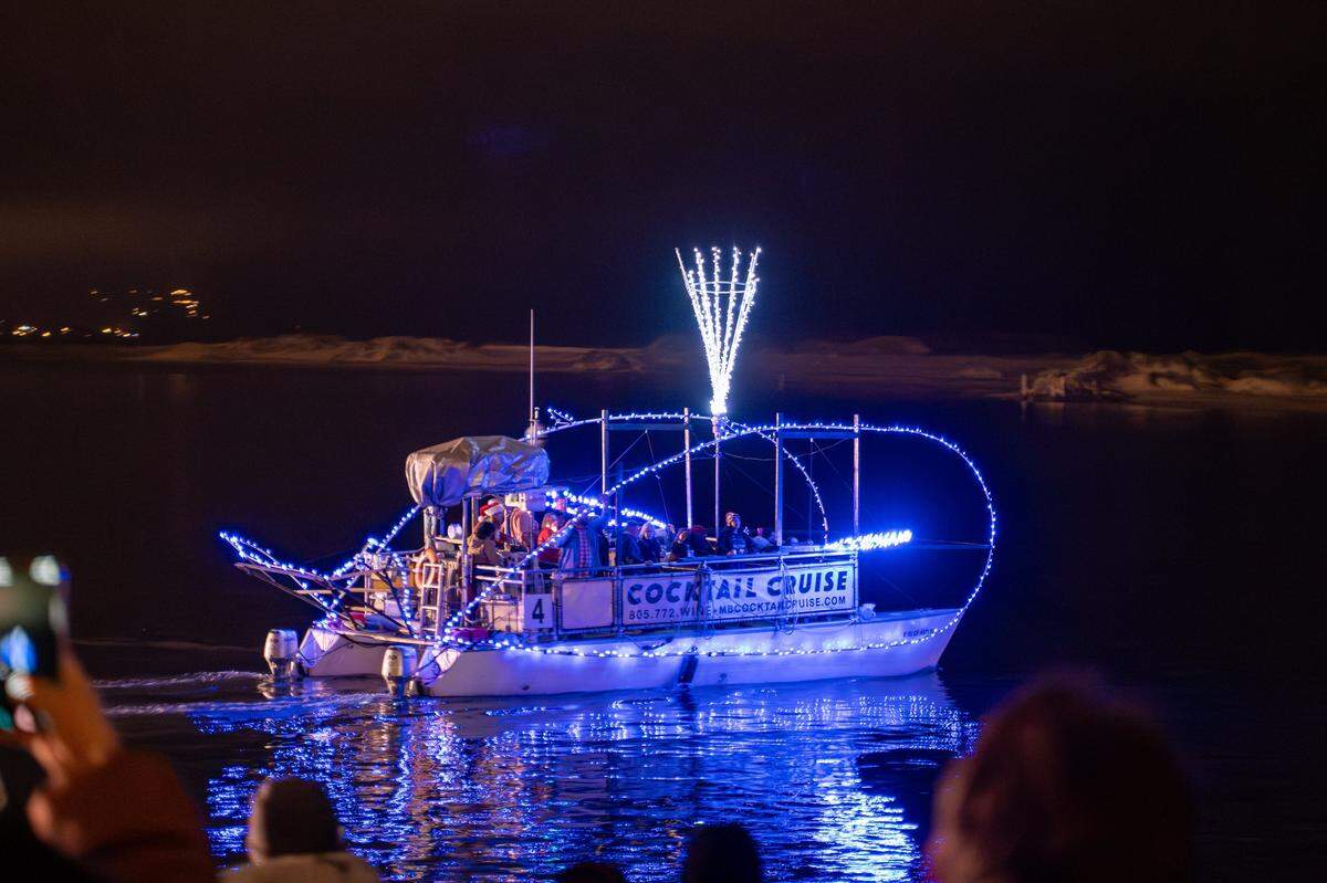 A boat made to look like a whale with a waterspout passes the pier in Morro Bay on Saturday, Dec. 13, 2025. The parade drew thousands of onlookers and dozens of boats equipped with festive lighting.