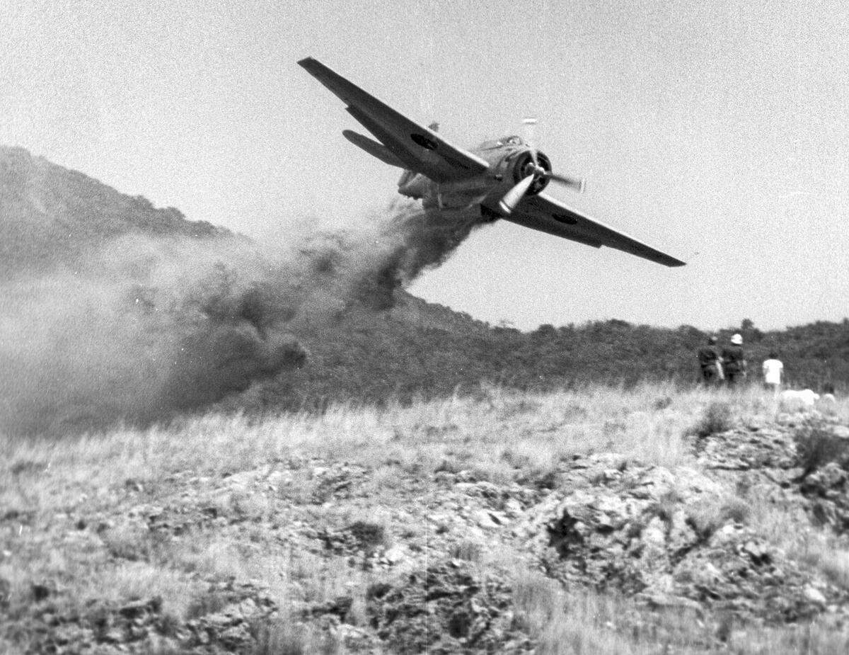Firefighters and spectators get extra-close look at a fire retardant bomber Sept. 17, 1973 on the hillside above San Luis High School.