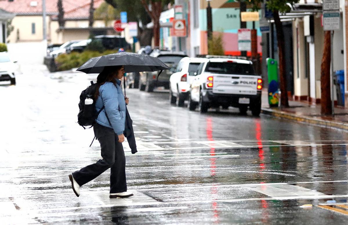 A woman crosses Broad Street in rainy San Luis Obispo on Thursday, Feb, 6, 2025. A winter storm brought heavy rain and strong winds to San Luis Obispo County on Thursday, with more on the way throughout the day and into Friday.