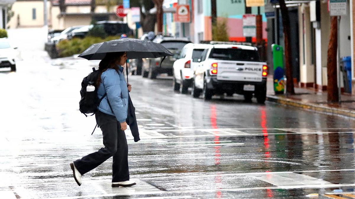 A woman crosses Broad Street in rainy San Luis Obispo on Thursday, Feb, 6, 2025. A winter storm brought heavy rain and strong winds to San Luis Obispo County on Thursday, with more on the way throughout the day and into Friday.