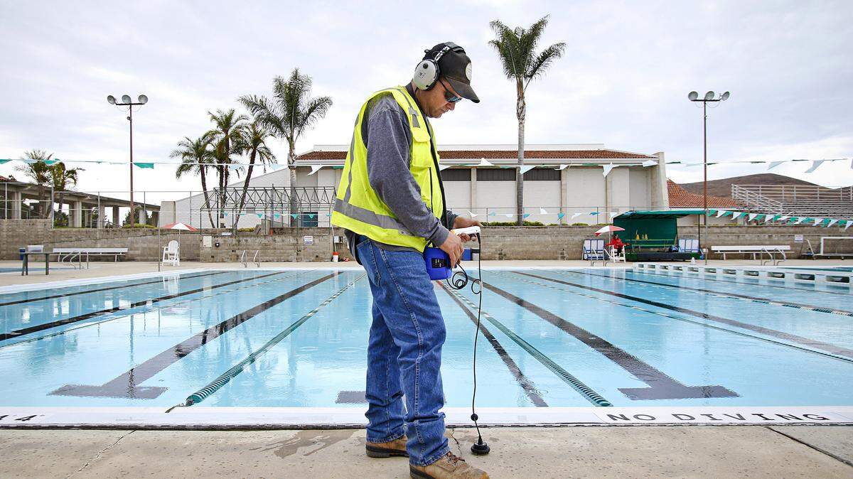 Chuck Elisarraras of All Private Utility Locating uses an acoustic listening device near the edge of the Cuesta College pool as he searches for a leak.