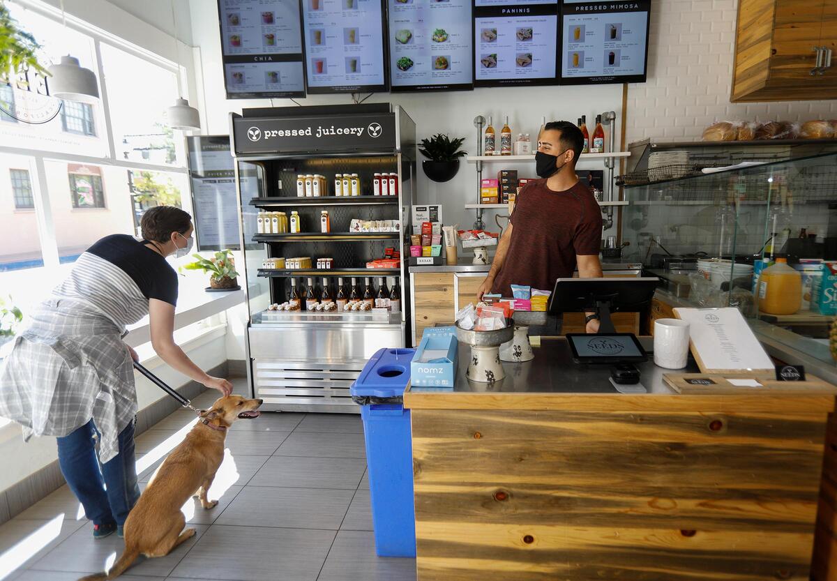 Downtown San Luis Obispo restaurants and businesses slowly reopen in May 2020. Seed’s owner Rammy Aburashed helps a customer that came in to the store.