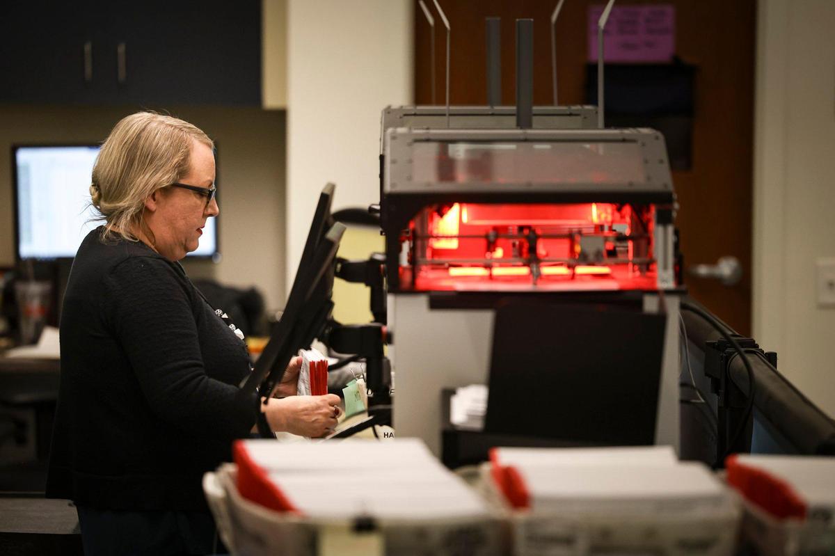 A red flashing light photographs signatures and records bar codes as Melanie Foster, deputy director clerk-recorder, runs mail-in ballots in batches of 200 at the San Luis Obispo County elections office Nov. 7, 2024.