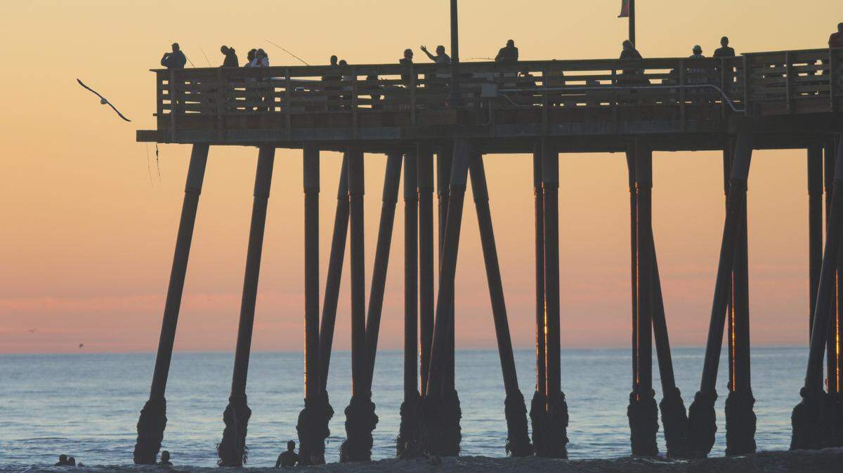 People enjoy fishing, surfing and selfies at sunset in Pismo Beach on Monday, Nov. 16, 2020.