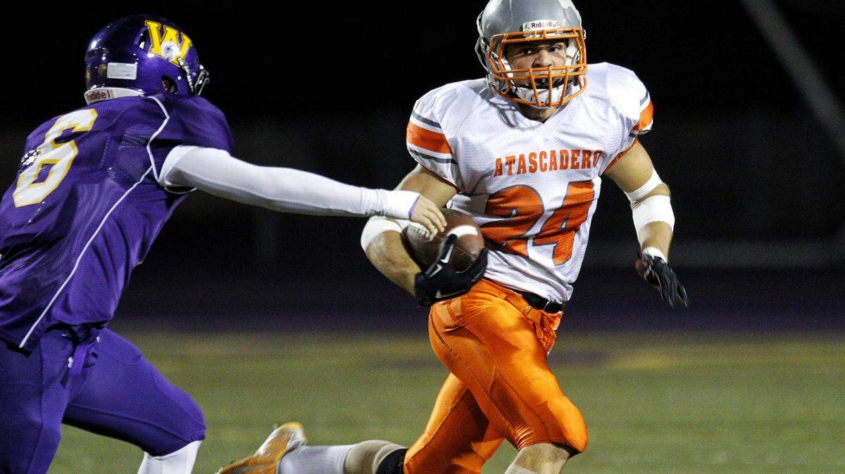 Atascadero High R.J. Reusche runs away from Righetti's Adam Portman during Friday night's game.