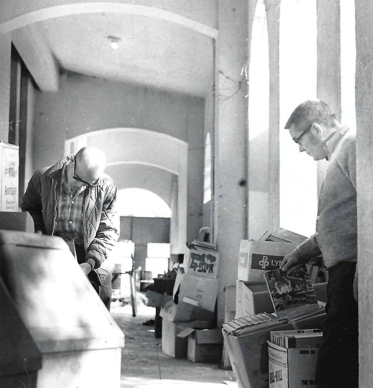 George Highland, left, and Preston Collie look over a crowded makeshift storage area at Atascadero High School in early October 1971.