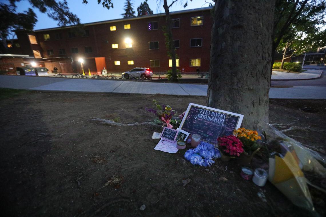 A memorial to Kristin Smart is in a grassy area between the red brick dorms at Cal Poly. The Sequoia Hall dorm is in the background.