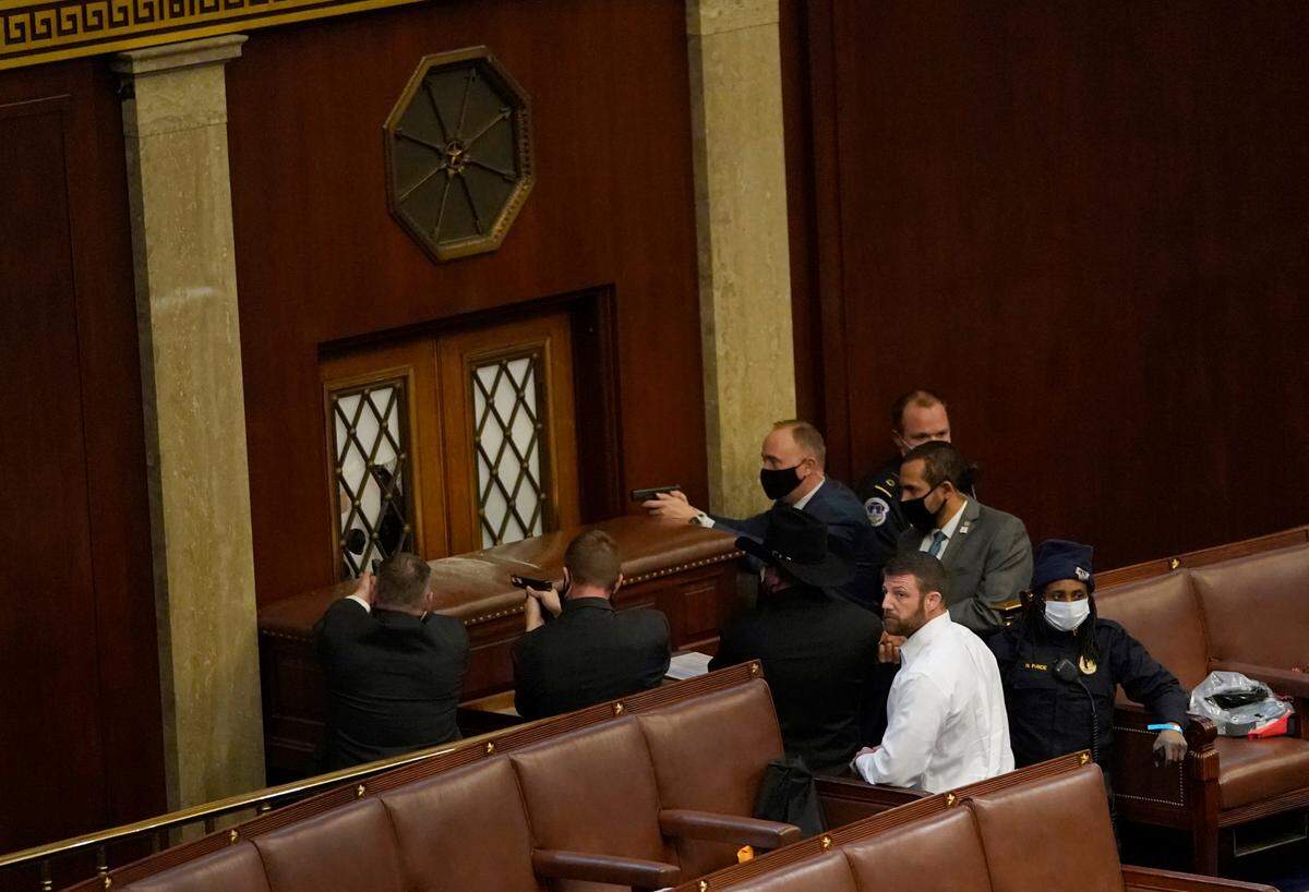 U.S. Capitol police officers point their guns at a door that was vandalized in the House Chamber during a joint session of Congress on Jan. 6, 2021 in Washington, D.C. Congress held a joint session today to ratify President-elect Joe Biden’s 306-232 Electoral College win over President Donald Trump. A group of Republican senators said they would reject the Electoral College votes of several states unless Congress appointed a commission to audit the election results.