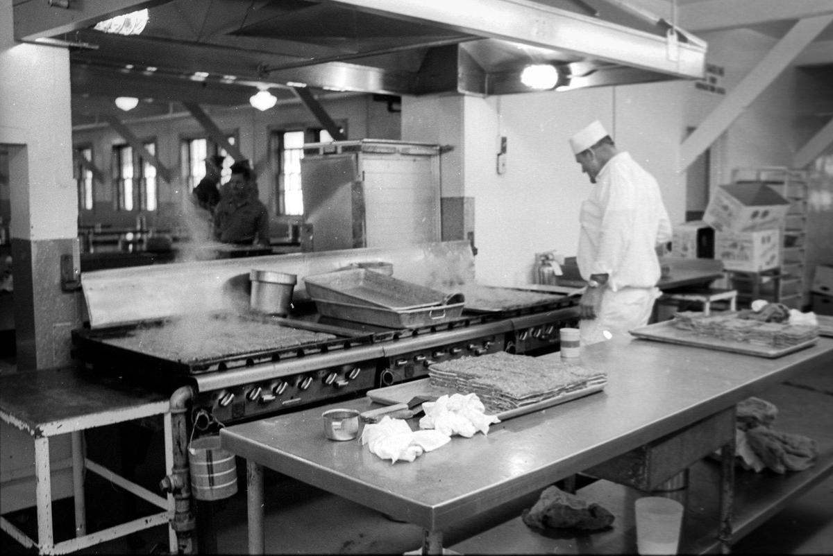 A cook prepares meat patties for inmates at the largest of three mess halls at the West Facility, the imates eat at tables to the left. California Mens Colony West facility tour on Dec. 2, 1970.