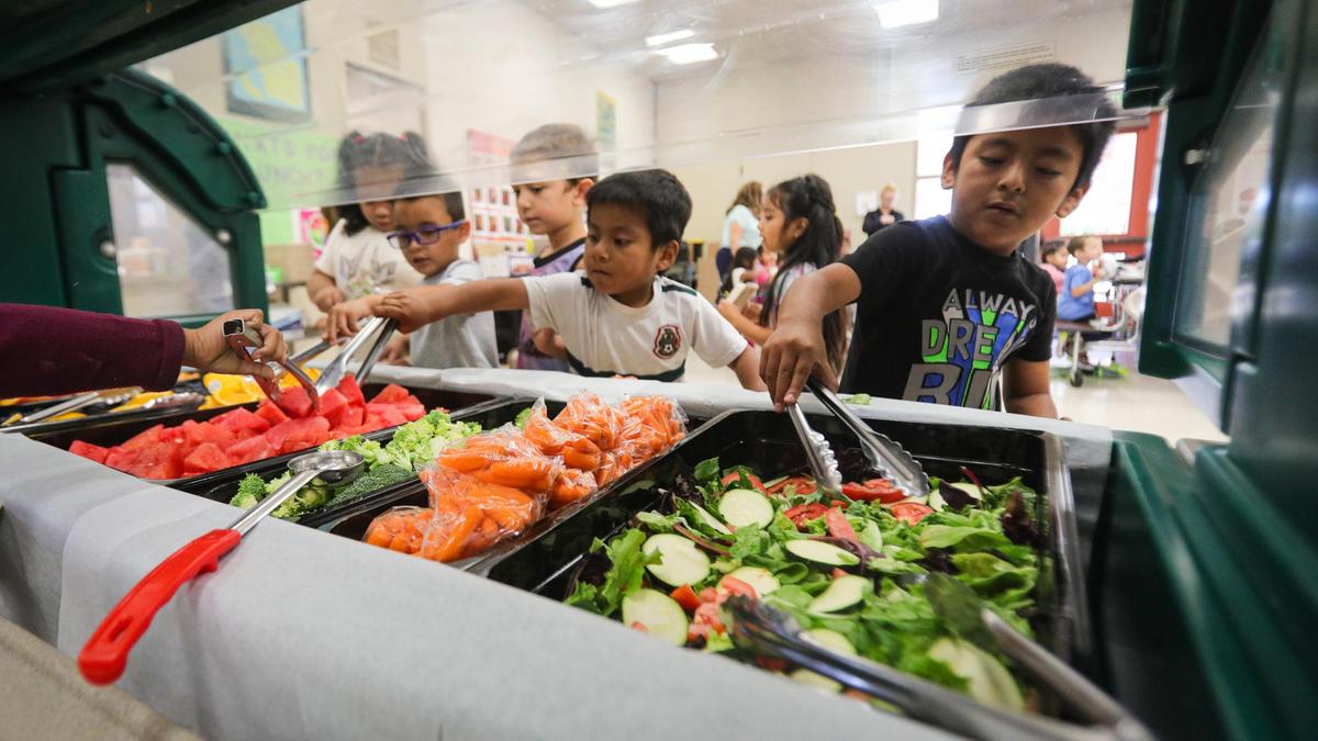 Students select fresh and local fruits and veggies before stepping up to the serving area where they will get spaghetti at Lillian Larsen Elementary in San Miguel on Aug. 22, 2022.