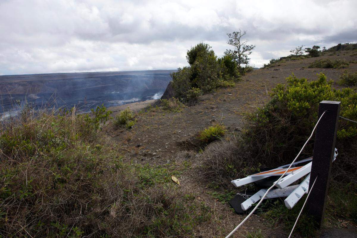 A construction sign lays askew in front of the active volcano, Kīlauea, on Sunday, March 22, 2025 at Hawaii Volcanoes National Park.