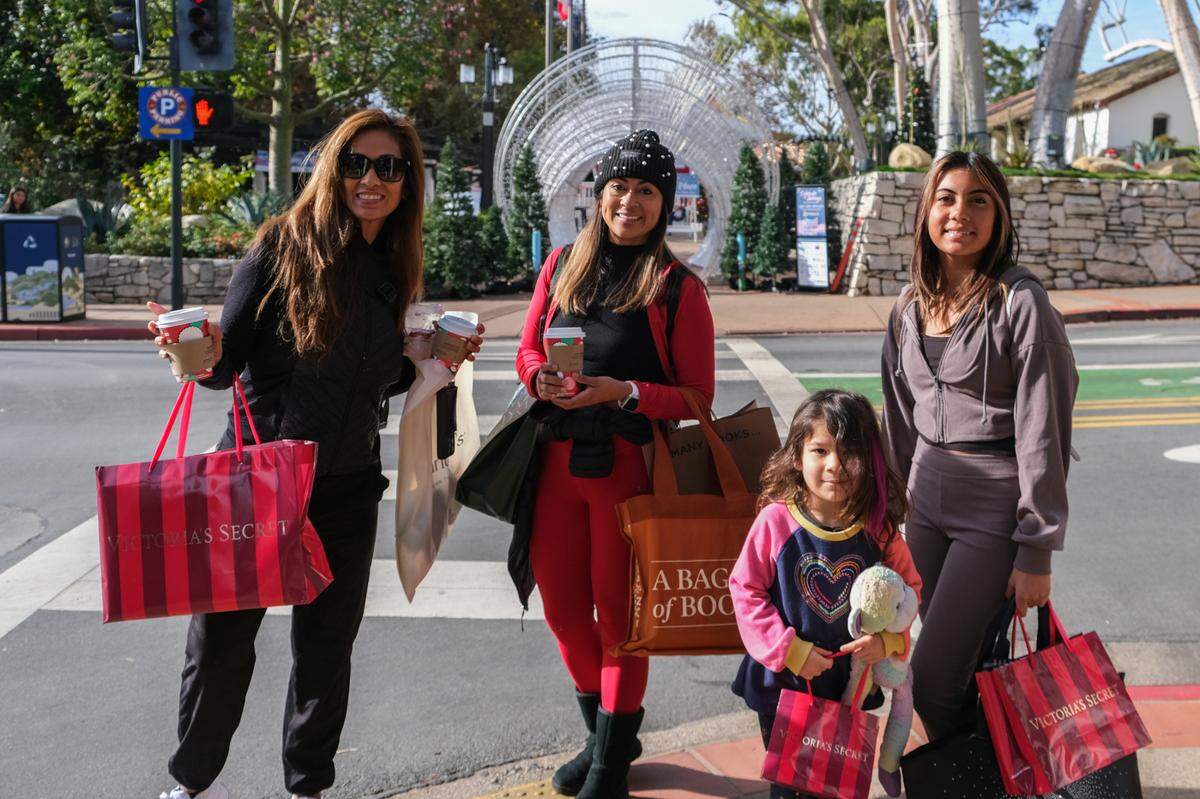 Sonya Olivas and her daughters pose with their shopping bags outside Mission Plaza in downtown San Luis Obispo on Black Friday, Nov. 29, 2024.