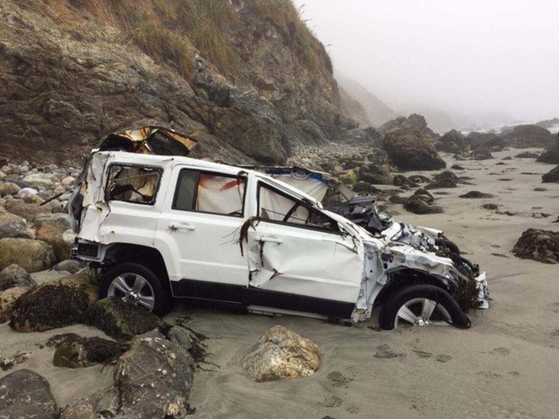 The wreckage of Angela Hernandez’s white 2011 Jeep Patriot rests in the water line Friday on a Big Sur beach.