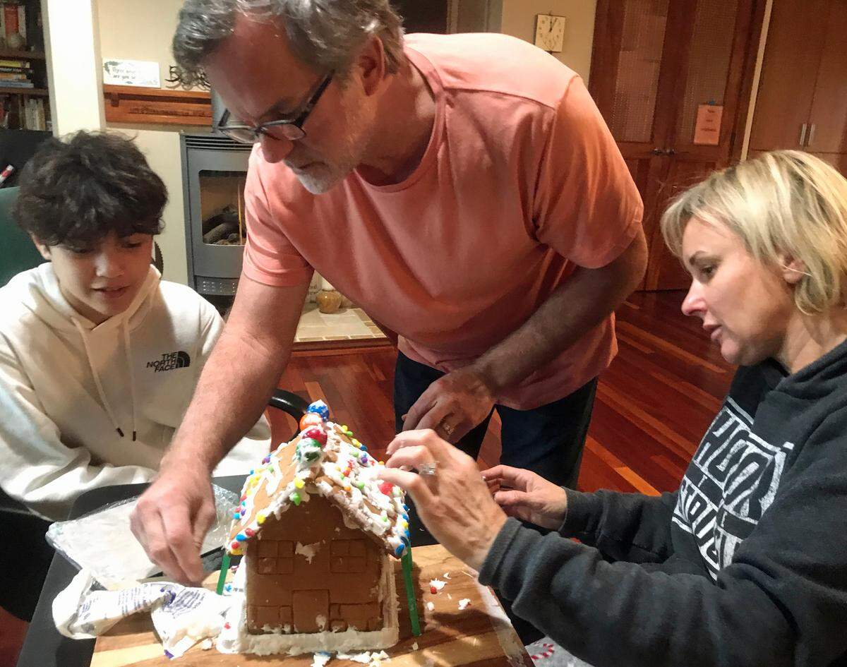 From left, Nico Prado, Sean Tanner and Jenny Tanner wrestle with a recalcitrant gingerbread house during a holiday visit.