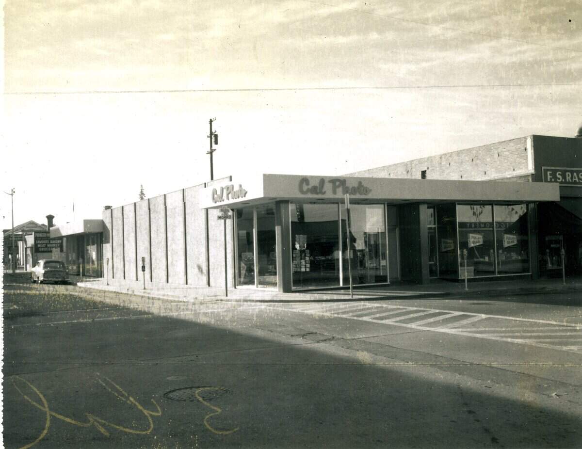 A Polaroid photograph of the Cal Photo store in a Mic-Century Modern building at the corner of Morro and Higuera streets, Oct. 5, 1959. Markings on the image can be seen for page cropping including a marking on the back to crop the image to three columns wide. Parking meters were installed. This is now the site of the Apple Store.