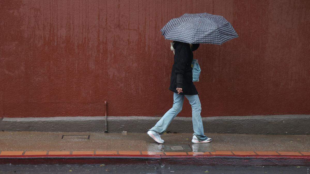A pedestrian walks down Osos Street in the rain as a storm hit San Luis Obispo on Feb. 16, 2026.